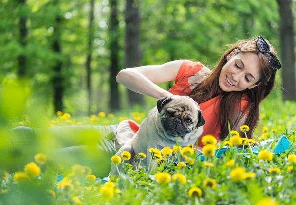 Pies rasy Mops. Dziewczyna jest chodzenie psa na zielony trawnik. — Zdjęcie stockowe