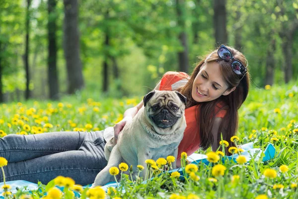 Hund der Rasse Mops. ein Mädchen geht mit einem Hund auf einem grünen Rasen spazieren. — Stockfoto