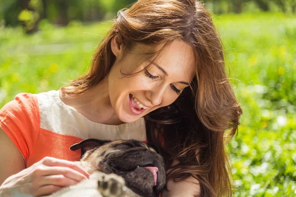 Hond van het ras van de mopshond. Een meisje loopt een hond op een groen gazon. — Stockfoto