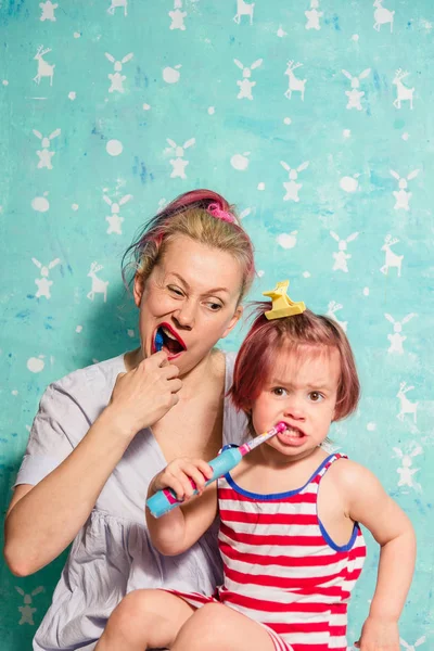 Cepillo de dientes. Mamá enseña a una pequeña hija a cepillarse los dientes —  Fotos de Stock