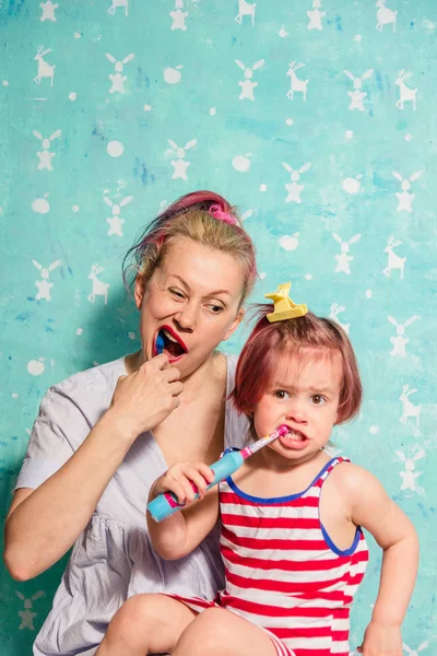 Toothbrush. Mom teaches a little daughter to brush their teeth