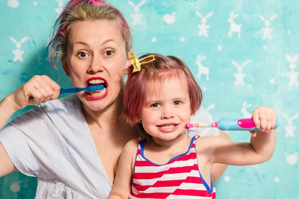 Toothbrush. Mom teaches a little daughter to brush their teeth