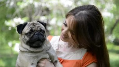 Pug doğurmak köpek. Bir kız bir köpek yeşil çimenlerin üzerinde yürüyor.