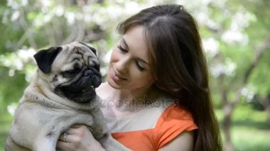 Pug doğurmak köpek. Bir kız bir köpek yeşil çimenlerin üzerinde yürüyor.