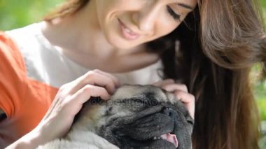 Pug doğurmak köpek. Bir kız bir köpek yeşil çimenlerin üzerinde yürüyor.