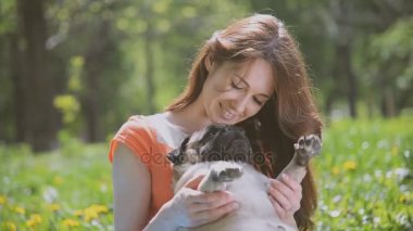 Pug doğurmak köpek. Bir kız bir köpek yeşil çimenlerin üzerinde yürüyor.