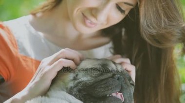 Pug doğurmak köpek. Bir kız bir köpek yeşil çimenlerin üzerinde yürüyor.