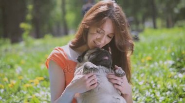 Pug doğurmak köpek. Bir kız bir köpek yeşil çimenlerin üzerinde yürüyor.