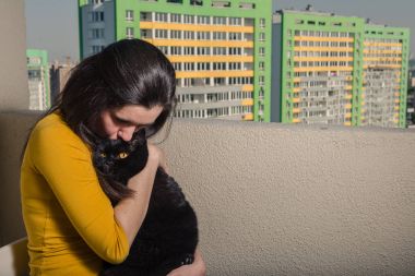 Siyah bir kedi bir kızla balkonundan için yeni bir yeri görünüyor.