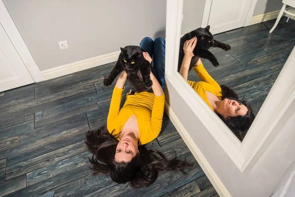 Interior. The girl is lying on the floor and is holding a black — Stock Photo, Image