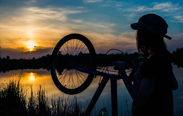 夕日を背景に自転車を持つ少女 — ストック写真