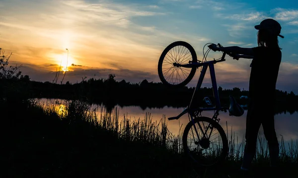 夕日を背景に自転車を持つ少女 — ストック写真