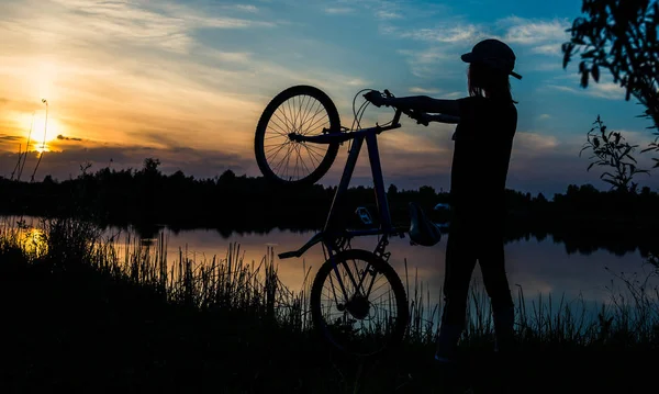 夕日を背景に自転車を持つ少女 — ストック写真