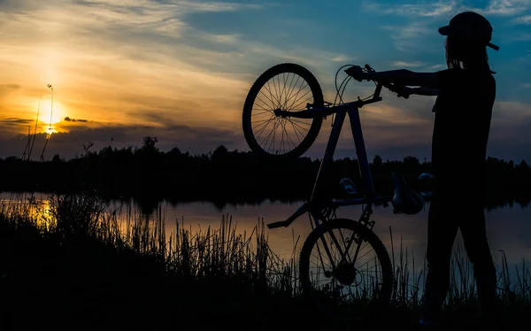 夕日を背景に自転車を持つ少女 — ストック写真