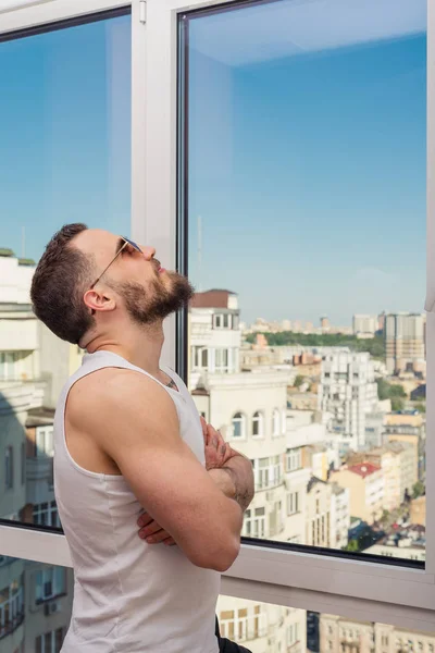 Ένας άντρας με γένια που κοιτάζει έξω από το παράθυρο — Φωτογραφία Αρχείου
