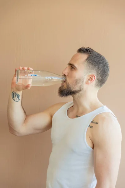 A guy with a beard drinks water — Stock Photo, Image