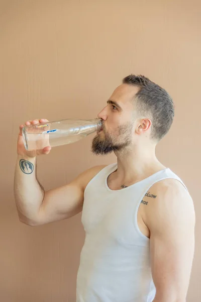 A guy with a beard drinks water — Stock Photo, Image