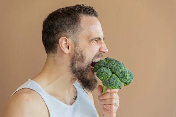 A guy with a beard sniffs broccoli — Stock Photo, Image