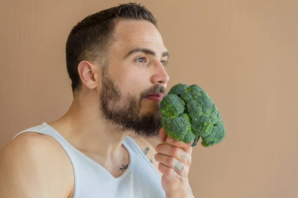 Un gars avec une barbe renifle le brocoli — Photo