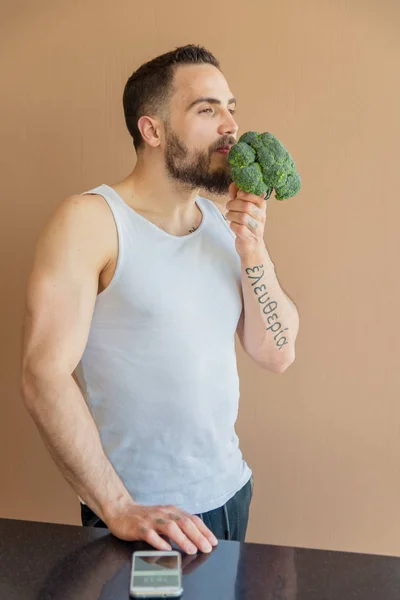 Chlap s plnovousem sniffs brokolice — Stock fotografie