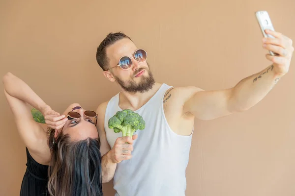 Un chico y una chica con brócoli hacen selfies —  Fotos de Stock