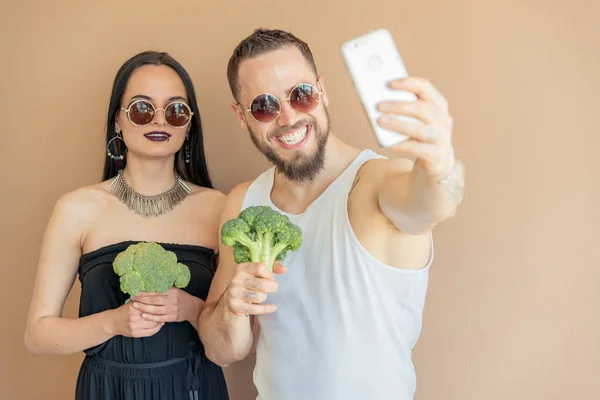 Un chico y una chica con brócoli hacen selfies — Foto de Stock