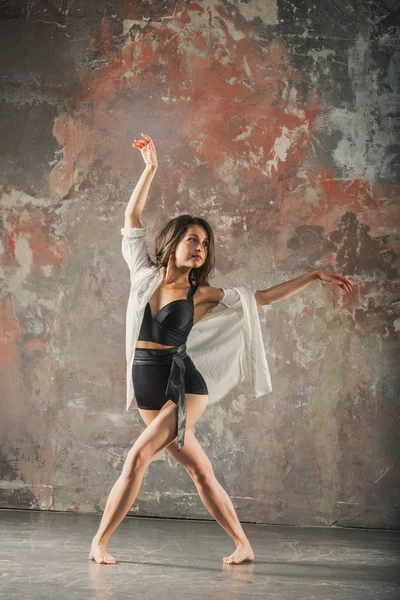 Menina dançando em um fundo de parede cinza — Fotografia de Stock