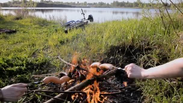 Пикник на природе. На костре варят сосиски — стоковое видео