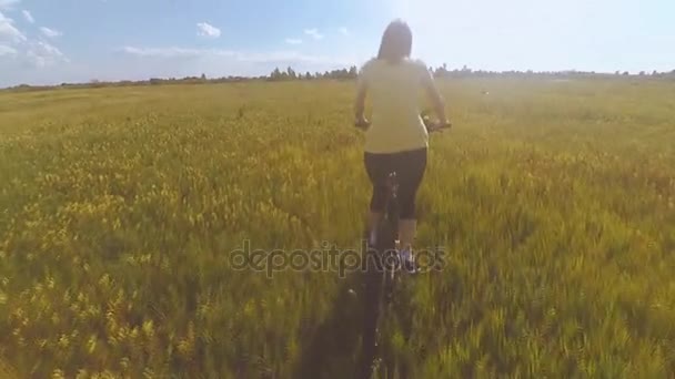 Flicka som rider en cykel på fältet — Stockvideo