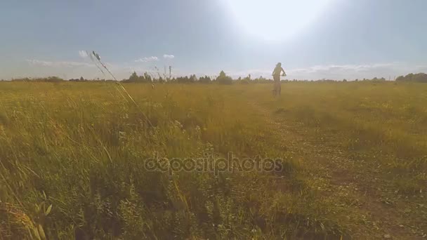 Flicka som rider en cykel på fältet — Stockvideo