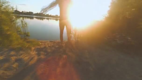 De man loopt naar het meer. — Stockvideo