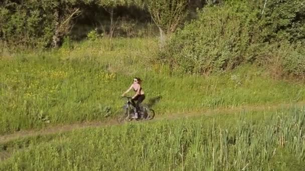 Meisje met een bergfiets in het veld — Stockvideo