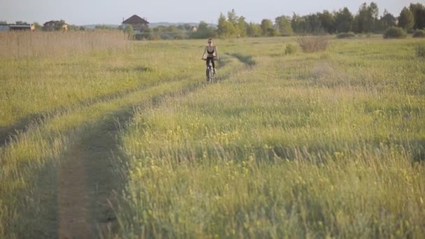 Chica montando una bicicleta de montaña en el campo — Vídeo de stock