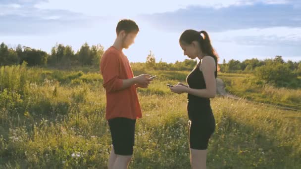 Mädchen und Mann in der Natur schauen in ein Handy — Stockvideo