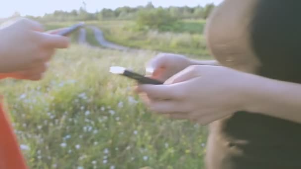 Menina e cara na natureza olhando em um telefone celular — Vídeo de Stock
