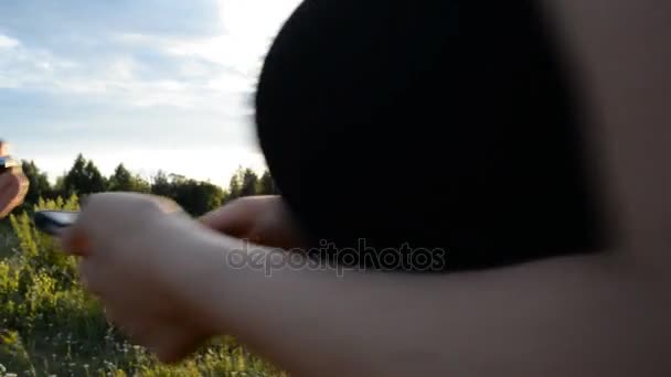 Chica y chico en la naturaleza mirando en un teléfono móvil — Vídeos de Stock