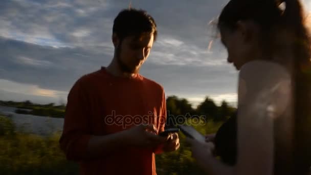 Meisje en jongen in de natuur op zoek in een mobiele telefoon — Stockvideo