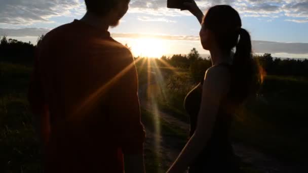 Девушка и парень в природе ищут в мобильном телефоне — стоковое видео