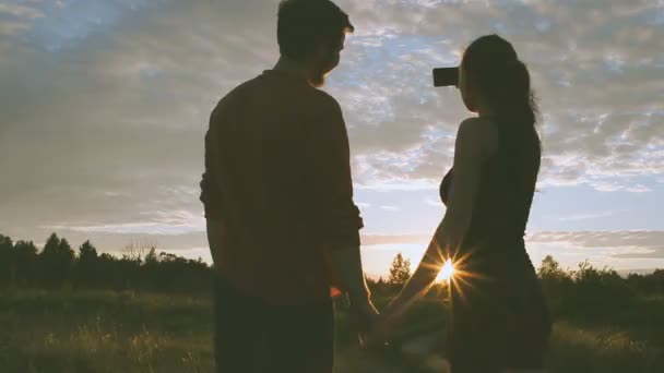 Meisje en jongen in de natuur op zoek in een mobiele telefoon — Stockvideo