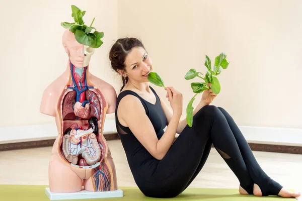 A yoga coach sits next to a medical dummy — Stock Photo, Image