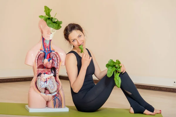 A yoga coach sits next to a medical dummy — Stock Photo, Image