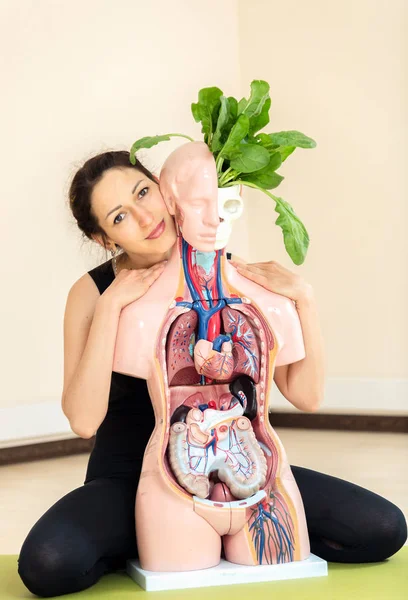 A yoga coach sits next to a medical dummy — Stock Photo, Image