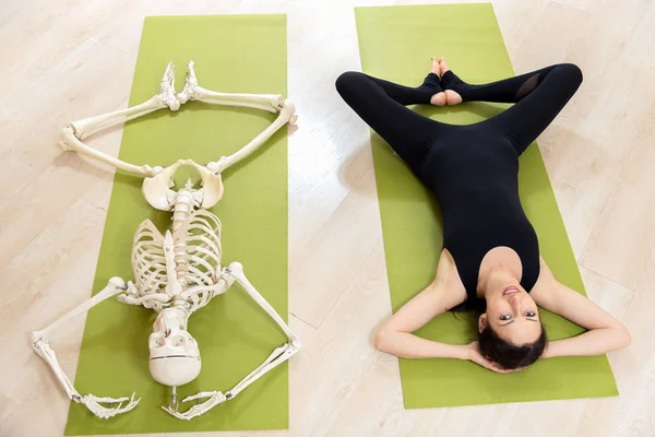 La chica se dedica al yoga junto con el esqueleto — Foto de Stock