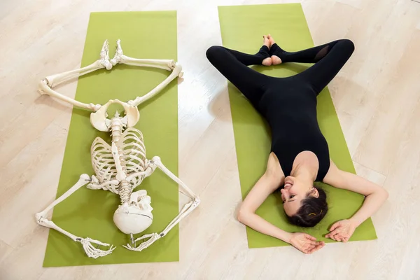 The girl is engaged in yoga along with the skeleton — Stock Photo, Image