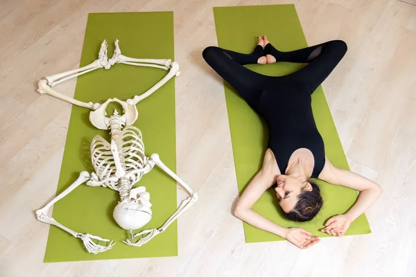 The girl is engaged in yoga along with the skeleton — Stock Photo, Image