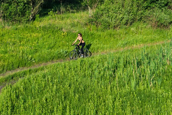 Ragazza in sella a una mountain bike nel campo — Foto Stock