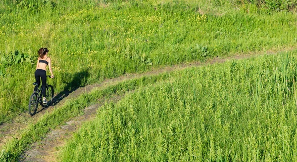 Ragazza in sella a una mountain bike nel campo — Foto Stock