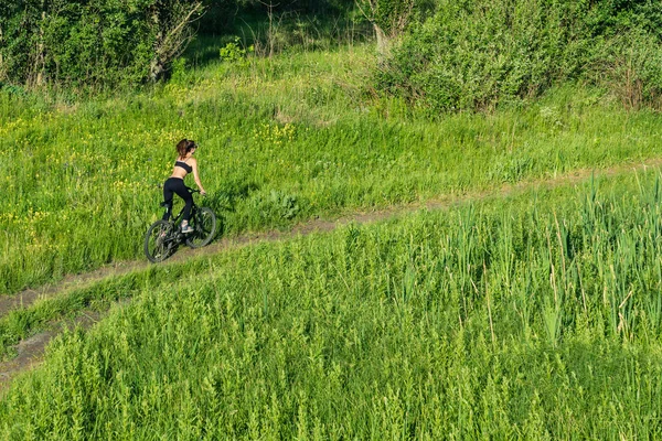 Girl riding a mountain bike in the field — Stock Photo, Image