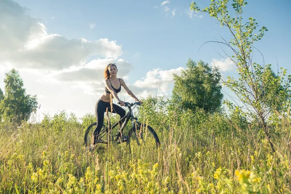Dívka na koni na horském kole v poli — Stock fotografie