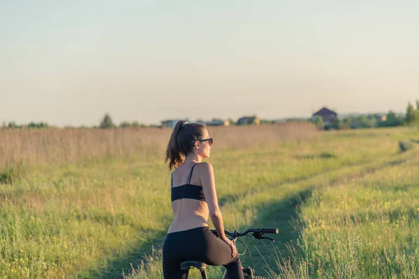 Chica montando una bicicleta de montaña en el campo — Foto de Stock